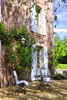 two chairs sitting in front of a building with blue shutters