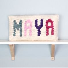 a crocheted pillow that says may on it sitting on top of a shelf