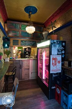 the interior of a small restaurant with neon signs on the wall and wooden flooring