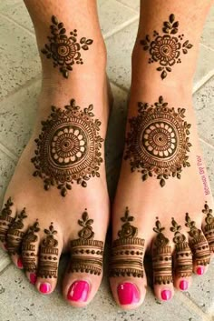 feet with henna tattoos on them and pink nail polishes in the bottom corner