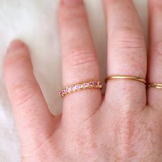 Nine 2.2mm Pink Sapphires set in 18k yellow gold - the stones have a soft pink hue with so much personality. Perfect for stacking or an unconventional wedding band! Pink Gemstone Stackable Rings In 14k Gold, Pink 14k Gold Stackable Ruby Ring, Stackable Pink Ruby Ring In 14k Gold, Gold Stackable Rings With Pink Sapphire, Fine Jewelry Pink Ruby Ring With Round Band, Pink Ruby Ring With Round Band In Fine Jewelry, Pink Gemstone Stackable Rings For Wedding, Yellow Gold Stackable Rings With Pink Sapphire, Stackable Pink Sapphire Rings With Round Cut