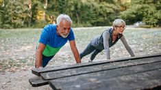 an older man and woman doing push ups in the park