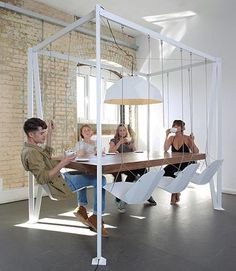 a group of people sitting around a table in a room with white walls and windows