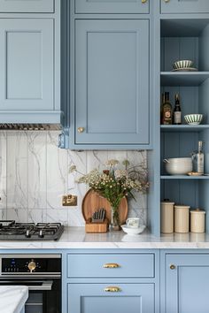 a kitchen with blue cabinets and marble counter tops, gold pulls on the cupboards