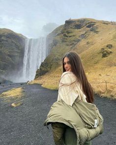 a woman standing in front of a waterfall