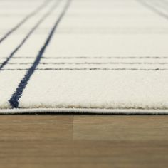 a white rug with blue lines on the bottom and sides is sitting on a wooden floor