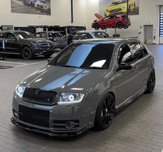 a grey car parked in a showroom next to other cars