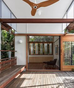 the ceiling fan is hanging in front of an open room with wooden floors and windows