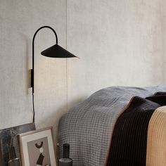 a bed with a black lamp on the wall next to it and a picture frame