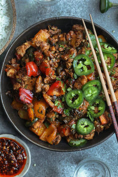 a bowl filled with meat and vegetables next to chopsticks on top of rice