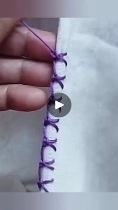 someone is stitching something with purple thread