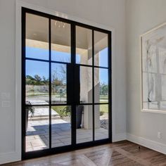 an empty room with large glass doors and wood flooring on the other side of the door