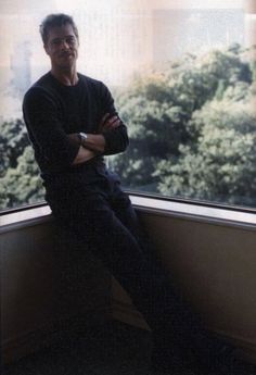 a man sitting in front of a window with his arms crossed