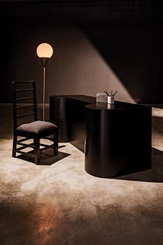 a chair and table in a dark room with a lamp on the floor next to it