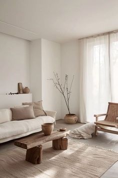 a living room filled with furniture and a window covered in white draping next to a wooden coffee table