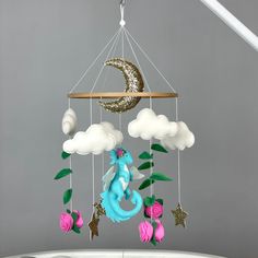 a mobile with a blue dragon and pink roses hanging from it's side on a gray background