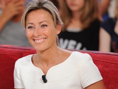 a smiling woman sitting on top of a red couch next to other people in the background