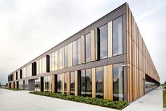 an office building with many windows and plants on the outside wall, in front of it