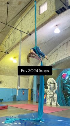 a woman doing aerial acrobatic tricks on a pole in an indoor gym