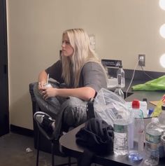 a woman sitting in a chair holding a cell phone and looking at her reflection in the mirror