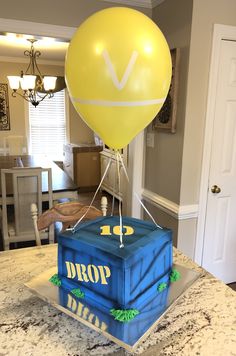 a birthday cake made to look like a box with a balloon on top that says drop