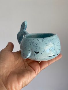 a hand holding a small blue whale shaped cup with stars on it's body