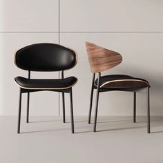 two black chairs sitting next to each other in front of a white wall and floor