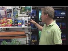 a man in a store pointing at something on the shelf with other items behind him