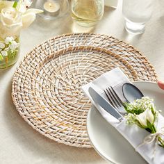 a table setting with white flowers and silverware