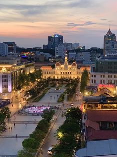 an aerial view of a city at dusk with buildings and trees in the foreground