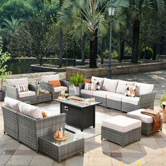 an outdoor patio with lots of furniture and trees in the background, including a coffee table