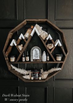 a wooden shelf with candles and other items on it in front of a black wall