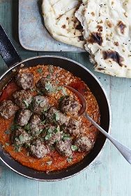 meatballs and tomato sauce in a skillet with pita bread on the side