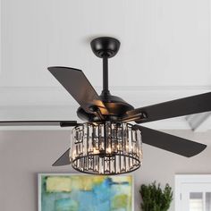 a black ceiling fan with crystal chandelier hanging from it's blades in a living room