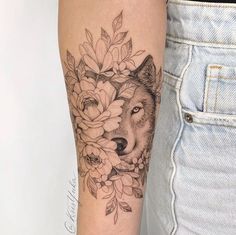 a woman's arm with a wolf and flowers tattoo on the left side of her body