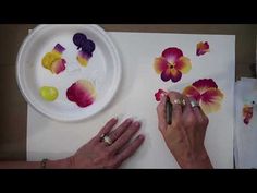 a woman is painting flowers on a paper plate with watercolors and crayons