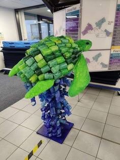 there is a sculpture made out of green and blue plastic bottles in the middle of a tile floor