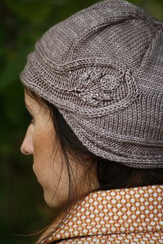 a woman wearing a gray knitted hat with an intricate design on the brim