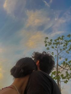 a man and woman are looking up at the sky with clouds in the back ground