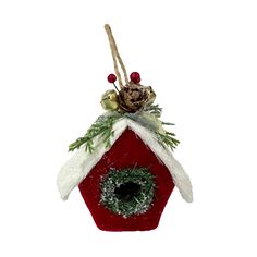 a red birdhouse with a wreath and pine cones hanging from it's roof