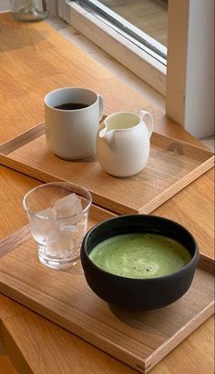 there is a bowl of soup and two cups on the table next to each other