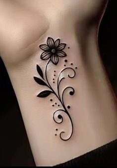 a black and white flower tattoo on the side of a woman's stomach,