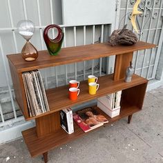 a book shelf sitting on the side of a sidewalk next to a building with an iron gate behind it