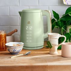 a green electric kettle sitting on top of a wooden table