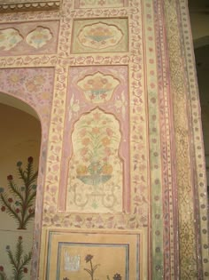 an intricately painted wall with flowers and leaves on it's sides, in the middle of a building