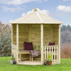 a wooden gazebo sitting on top of a lush green field