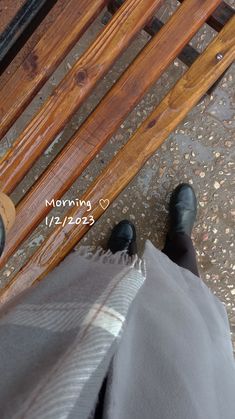 a person standing on top of a wooden bench next to another person wearing black shoes