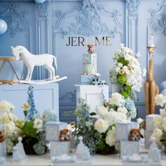 a table topped with lots of white flowers next to a blue and gold wallpaper