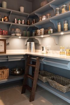 a kitchen with shelves filled with bottles and jars on top of the counter, next to a ladder