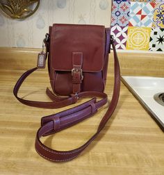 Very nice Coach Camera bag in burgundy leather 8 n h x 6 n w x 2.5 in deep with crossbody strap that has a shoulder protector. Inside has a zippered pocket with brown fabric interior and gold tone hardware. This style is hard to find and this one is in good condition. Formal Brown Shoulder Bag With Cell Phone Pocket, Burgundy Shoulder Bag For Fall, Formal Burgundy Shoulder Bag With Adjustable Strap, Classic Burgundy Bag With Adjustable Strap, Burgundy Satchel With Adjustable Strap For Formal Occasions, Classic Burgundy Shoulder Bag With Adjustable Strap, Classic Burgundy Shoulder Bag For Travel, Burgundy Leather Satchel For Fall, Classic Burgundy Shoulder Bag For Fall